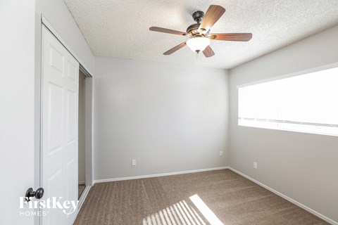 an empty room with a ceiling fan and a window