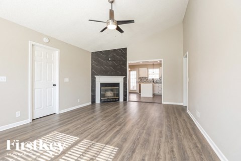 A spacious living room with a fireplace and a ceiling fan.