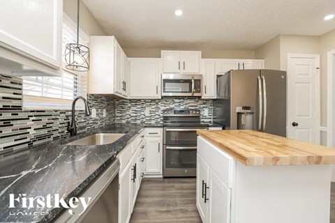 A kitchen with a wooden counter top and stainless steel appliances.