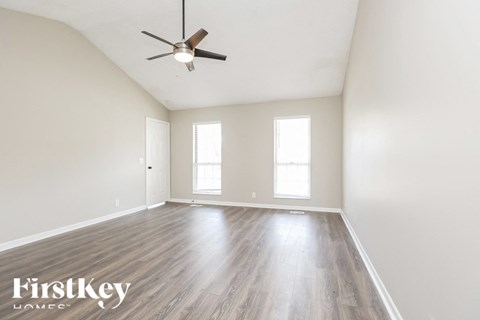 A spacious room with a ceiling fan and wooden flooring.