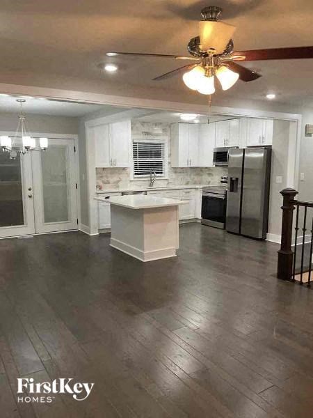a kitchen with a center island and a stainless steel refrigerator