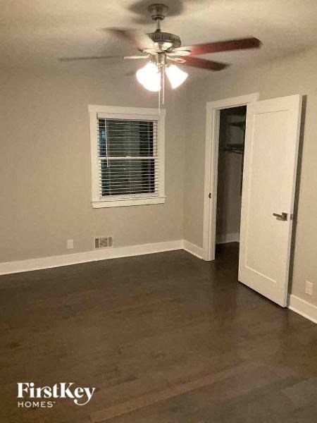an empty living room with a ceiling fan and a door