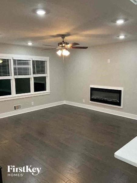 an empty living room with a ceiling fan and a fireplace