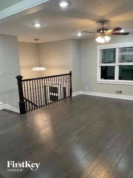 an empty living room with a ceiling fan and a staircase