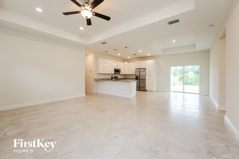an empty living room and kitchen with a ceiling fan