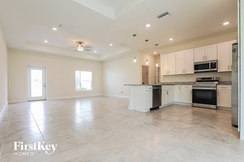 A spacious kitchen and living room with white cabinets and appliances.