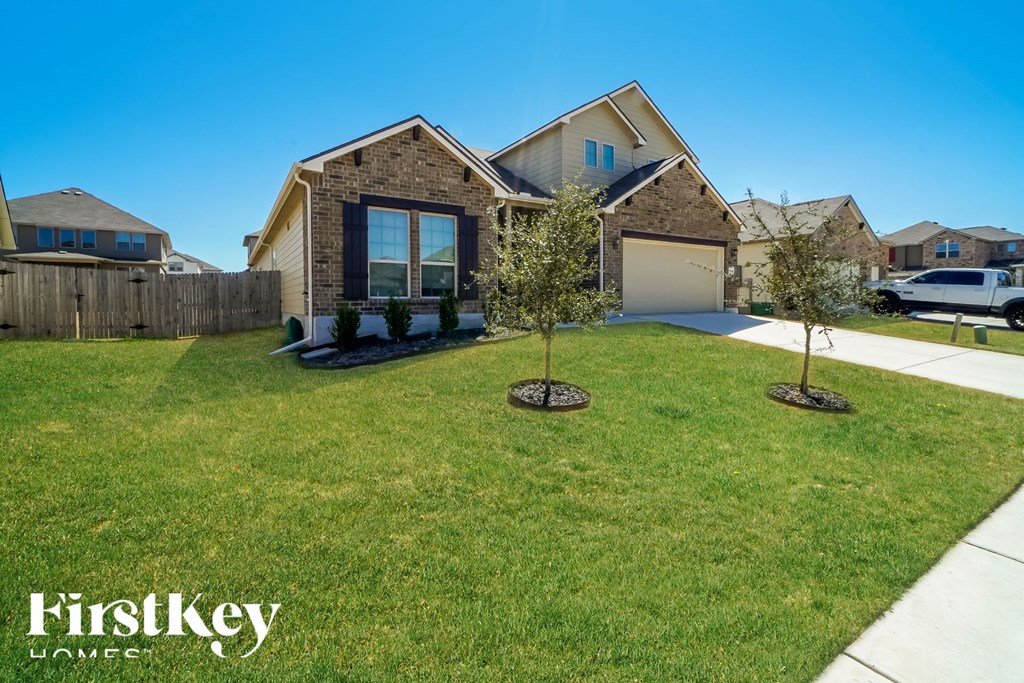a home with a lawn and two trees in front of it