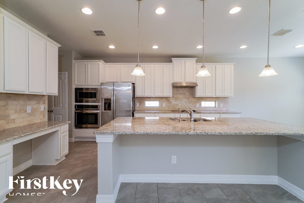 a kitchen with white cabinets and a marble counter top