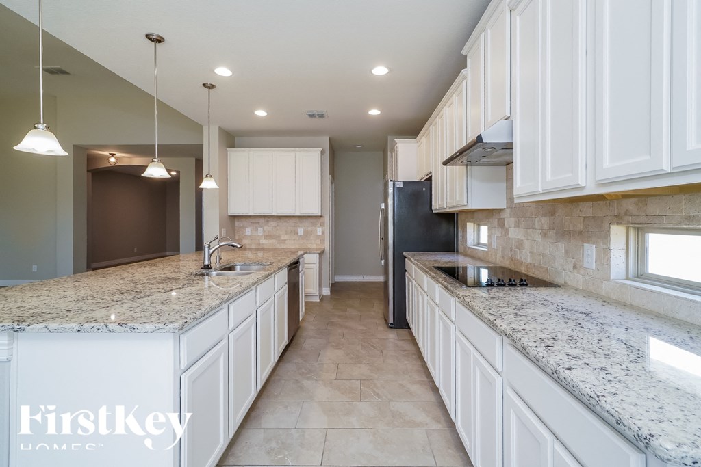 a large kitchen with white cabinets and granite counter tops