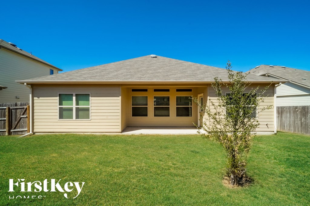 the front of a house with a lawn and a tree