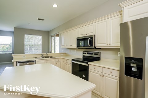 A kitchen with white cabinets and a stainless steel refrigerator.