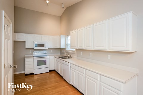 A kitchen with white cabinets and appliances.