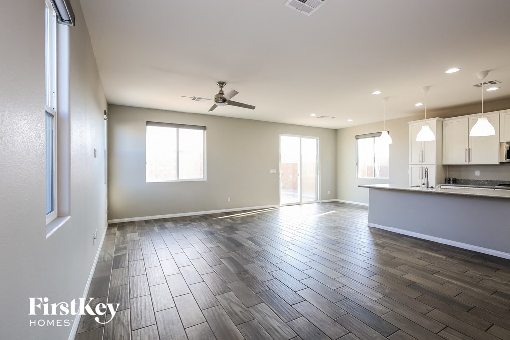 an empty living room and kitchen with a ceiling fan