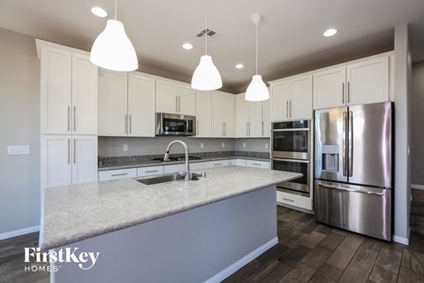 a kitchen with white cabinets and a marble counter top