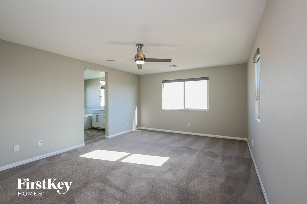 a empty living room with a ceiling fan and a window
