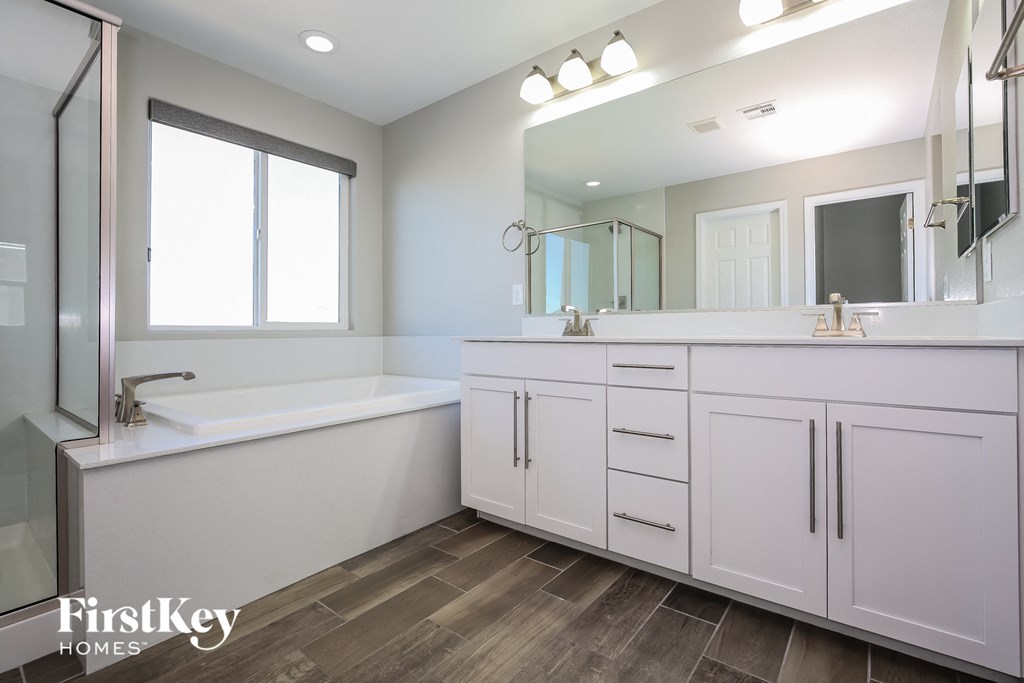 a bathroom with white cabinets and a tub and a sink