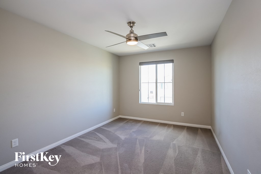 an empty room with a ceiling fan and a window