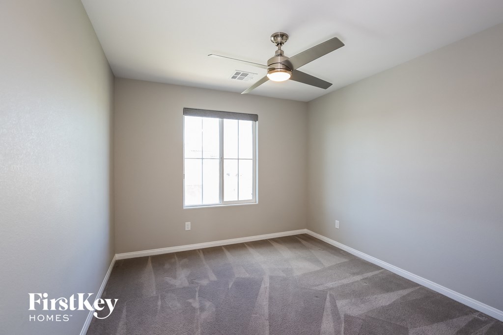 an empty room with a ceiling fan and a window