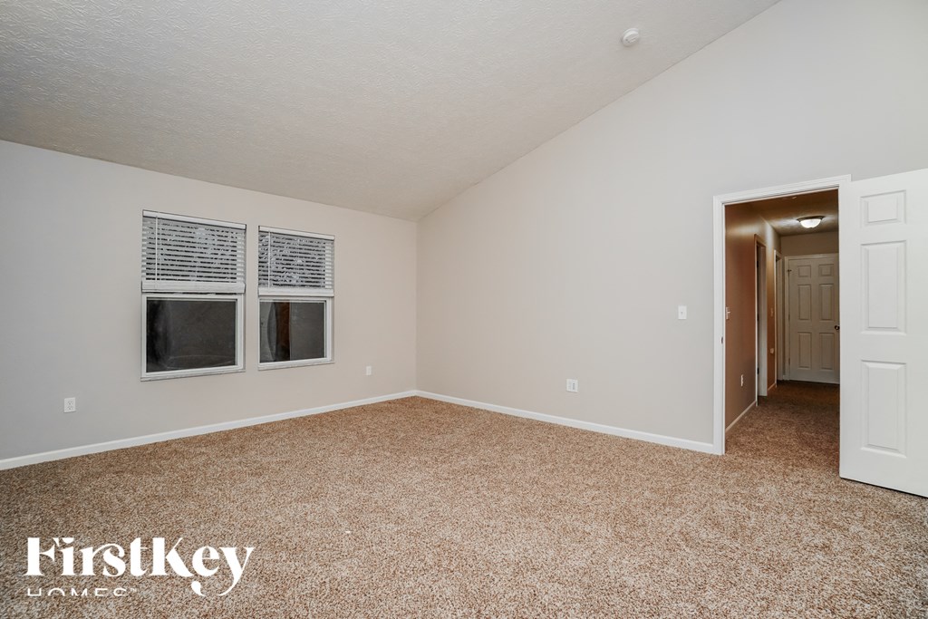 A room with a carpeted floor and two windows.