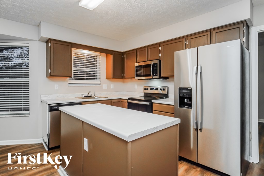 A kitchen with a white counter top and a refrigerator.