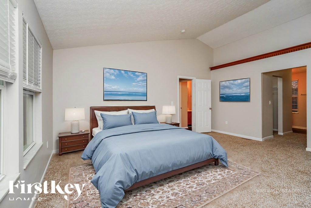 A bedroom with a large bed and a painting of a beach scene on the wall.