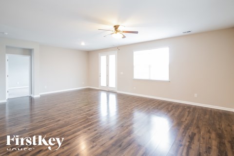 A spacious room with wooden floors and a ceiling fan.