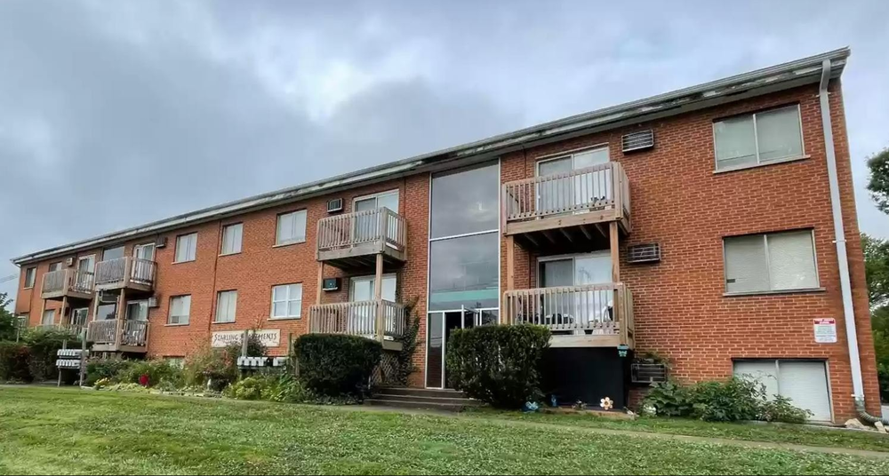 A red brick apartment building with a balcony on the second floor.