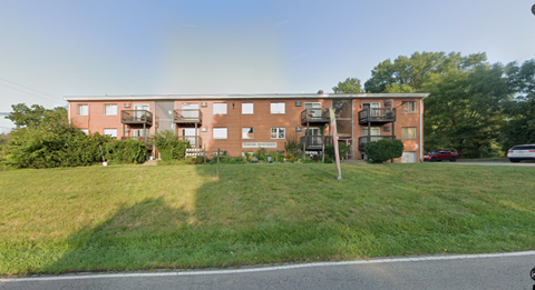 A red brick apartment building with a green lawn in front.