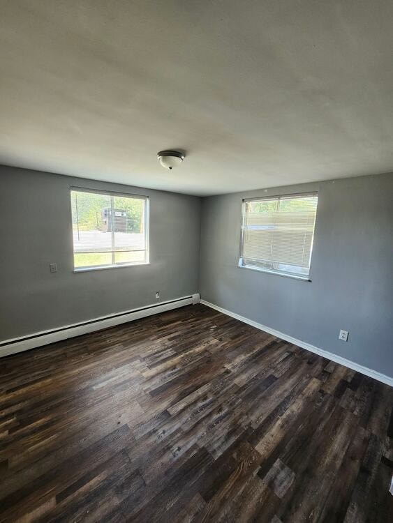 A room with wooden floors and two windows.