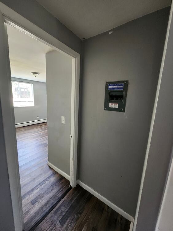 A hallway with a door and a control box on the wall.