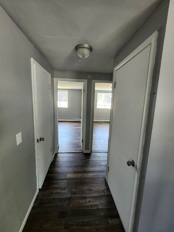 A long hallway with white walls and wood floors.