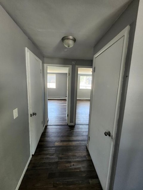 A long hallway with white walls and wood floors.