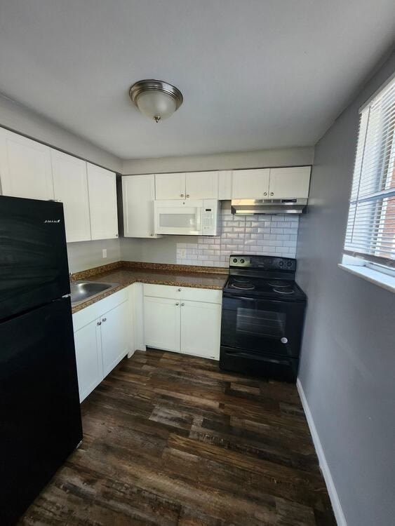 A kitchen with black appliances and white cabinets.