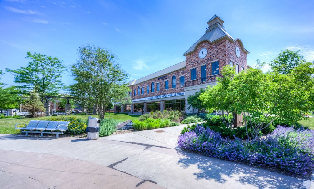 a building with a clock tower and benches in a park