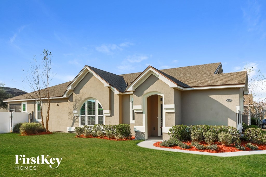 A house with a brown roof and a white fence is shown.