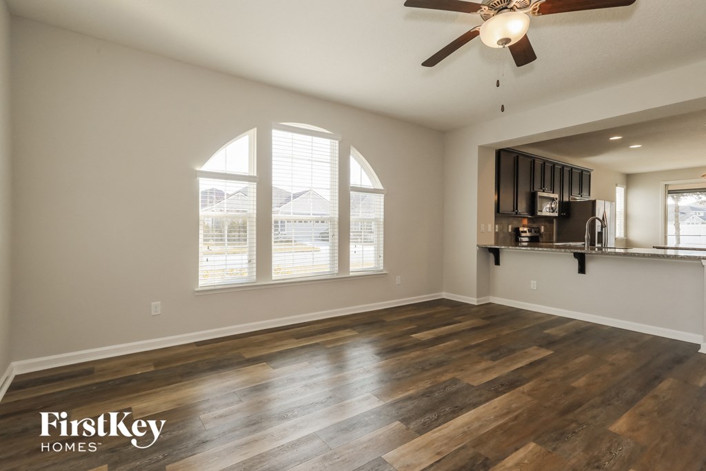 A spacious room with wooden floors and a ceiling fan.