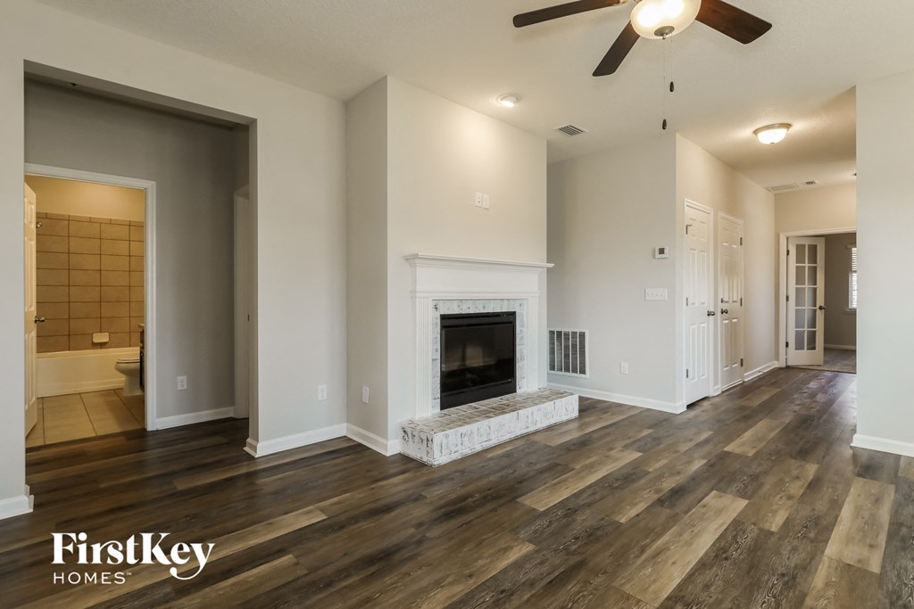 A spacious living room with wood flooring and a fireplace.