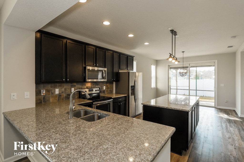 A kitchen with granite countertops and black cabinets.