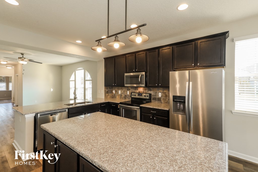 A kitchen with a granite countertop and stainless steel appliances.