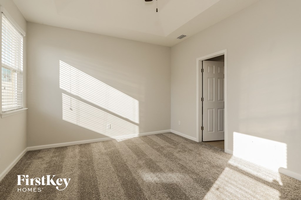 A room with a carpeted floor, a door, and a window with blinds.