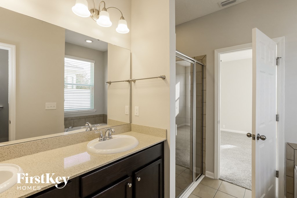 A bathroom with a sink, mirror, and shower.