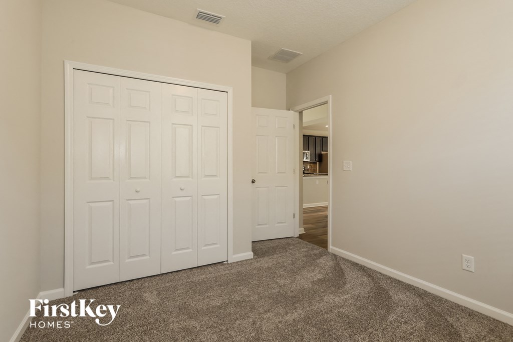 A carpeted room with a white door and a white wall.