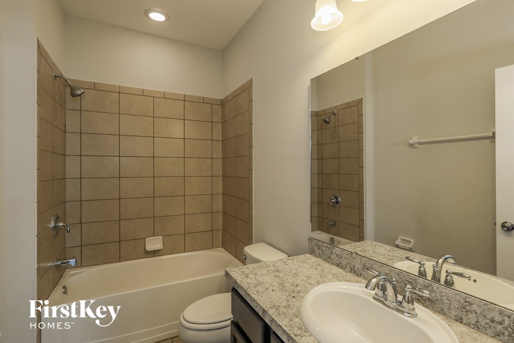 A bathroom with a tiled shower and a white sink.