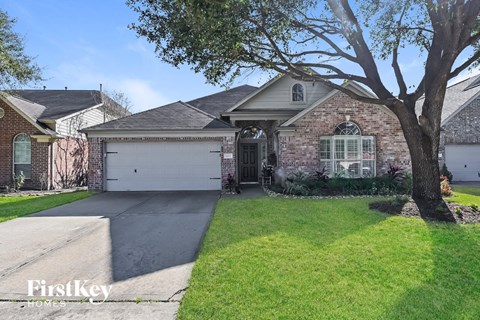 a brick house with a white garage door and a tree