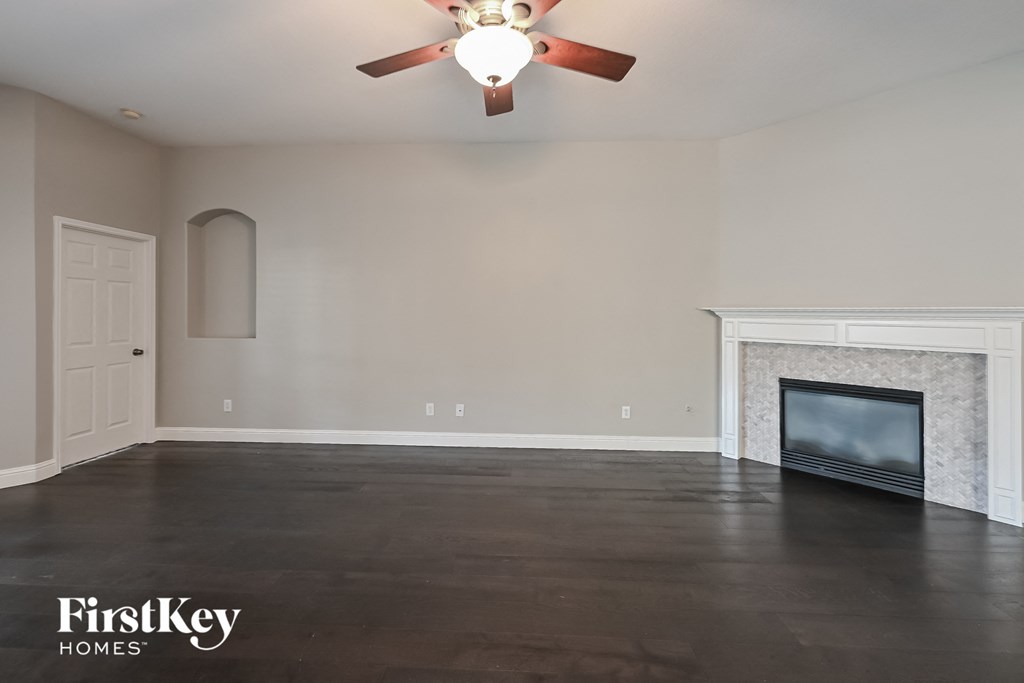 a empty living room with a ceiling fan and a fireplace