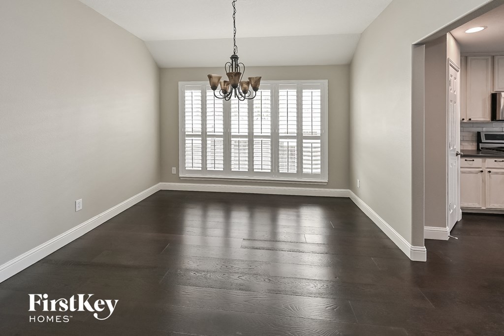 an empty living room with a window and a chandelier