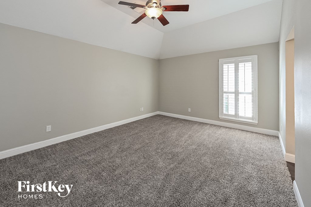 an empty room with a ceiling fan and a window