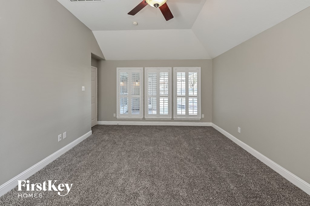 a spacious living room with carpet and a ceiling fan