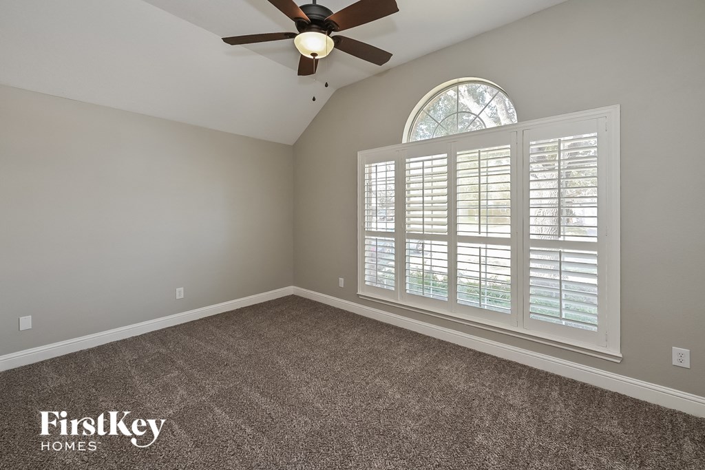 the master bedroom has a ceiling fan and a large window