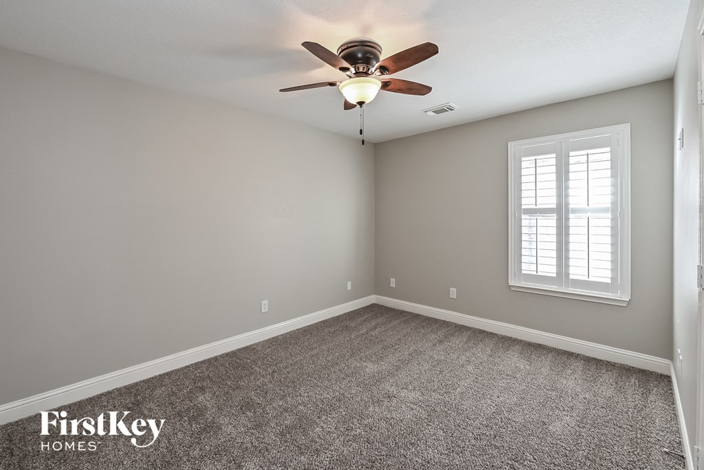 an empty room with a ceiling fan and a window